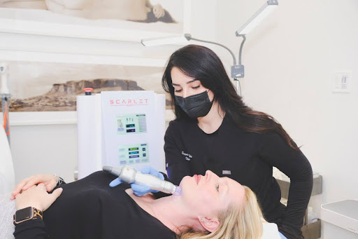 Aesthetician in black attire and mask performing a microneedling procedure on a female client at a clinic in Santa Fe, highlighting advanced skin rejuvenation techniques.