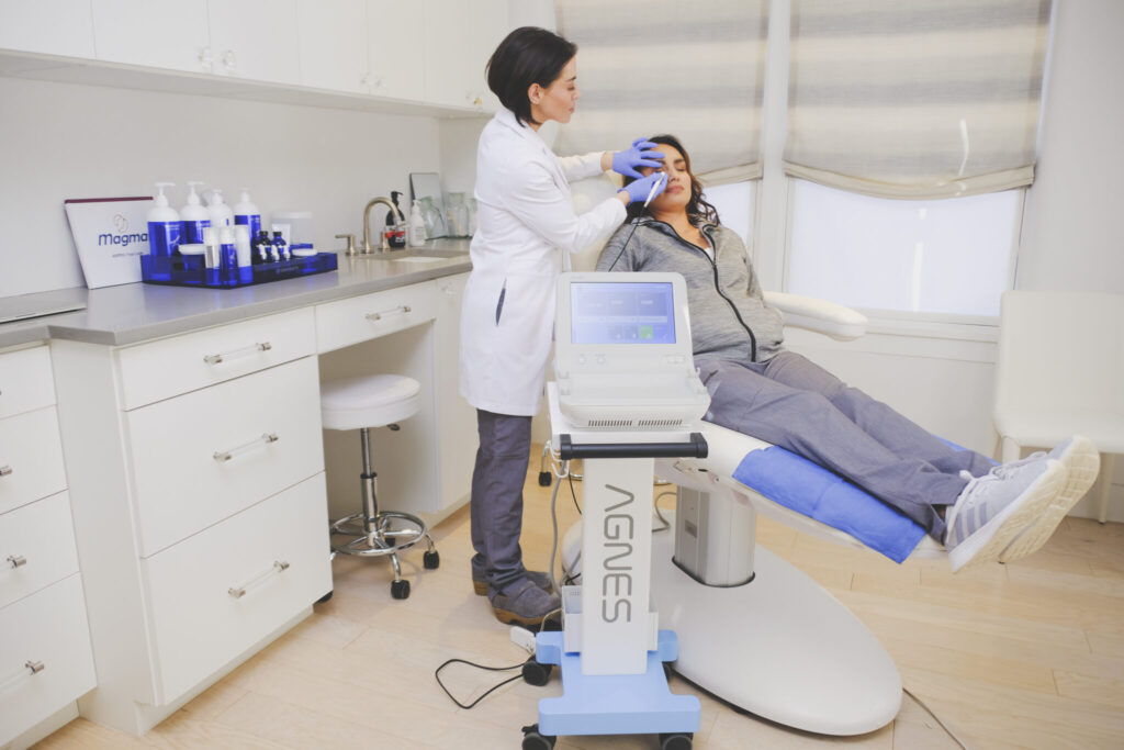 A skincare professional administers a scar reduction treatment using specialized equipment in a modern clinic in Santa Fe.