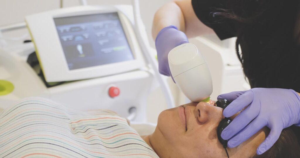 A skincare professional administers LED light therapy to a client's face at Seamless Skin MD in Santa Fe, using advanced equipment for enhanced skin health.