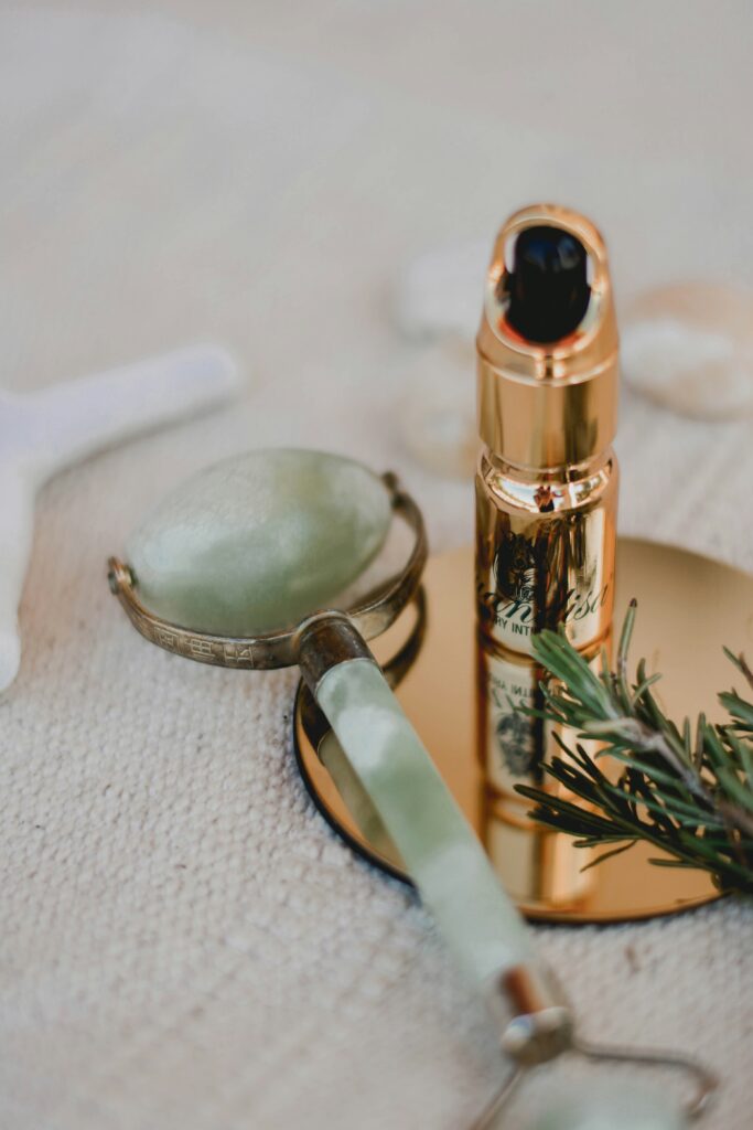 A jade roller and a gold serum bottle placed on a spa table, representing luxurious skincare tools used in Hydrafacial treatments in Santa Fe for deep hydration and skin rejuvenation.