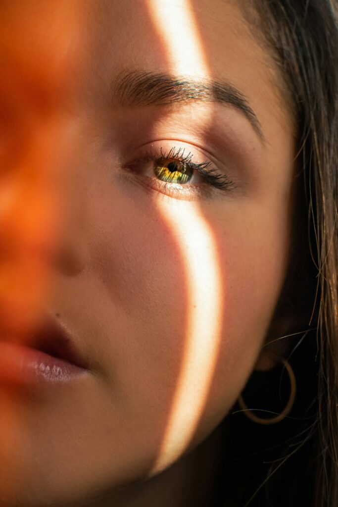 Close-up of a woman's face partially illuminated by sunlight, emphasizing skin tone and texture, relevant for showcasing melasma treatment solutions in Santa Fe.